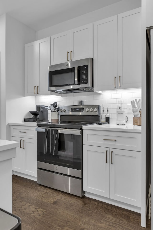 kitchen featuring white cabinetry, stainless steel appliances, backsplash, and dark hardwood / wood-style floors