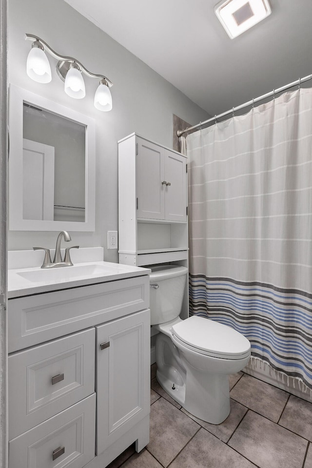 bathroom featuring toilet, walk in shower, vanity, and tile patterned flooring