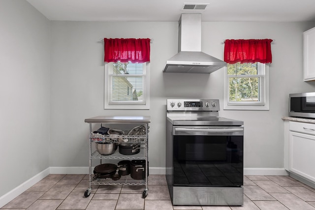 kitchen with wall chimney range hood, a healthy amount of sunlight, appliances with stainless steel finishes, and white cabinetry