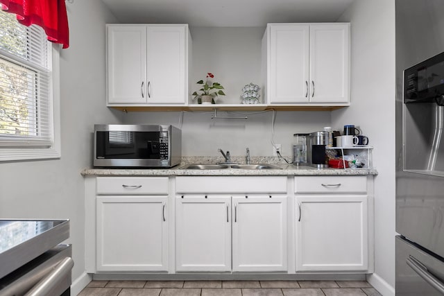 kitchen with light tile patterned floors, stainless steel appliances, sink, and white cabinets