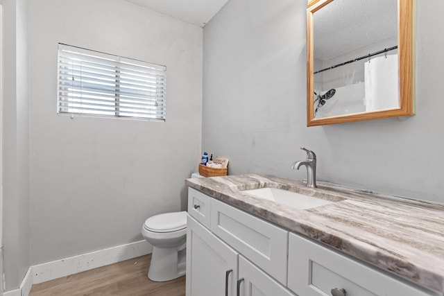 bathroom with hardwood / wood-style flooring, toilet, curtained shower, vanity, and a textured ceiling