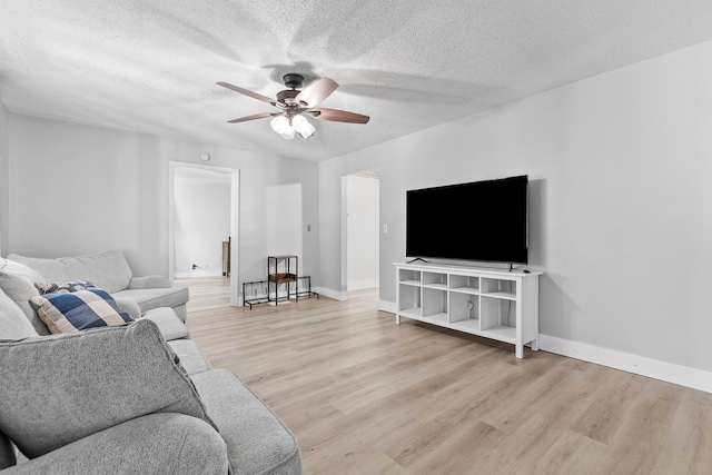 living room with light hardwood / wood-style flooring, a textured ceiling, and ceiling fan