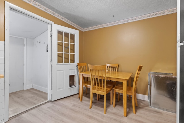 dining space featuring lofted ceiling, crown molding, a textured ceiling, and light wood-type flooring