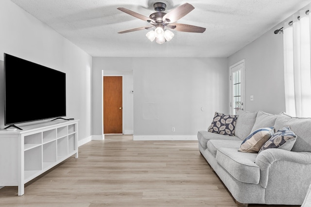 living room featuring light hardwood / wood-style floors, a textured ceiling, and ceiling fan