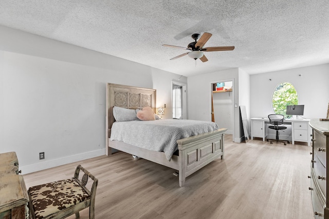 bedroom featuring light hardwood / wood-style floors, a textured ceiling, a walk in closet, and ceiling fan