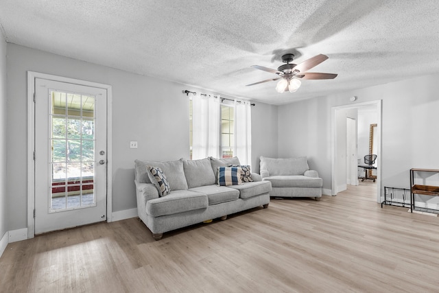 living room featuring a textured ceiling, light wood-type flooring, and ceiling fan