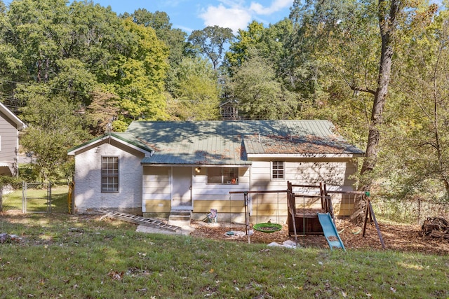 back of house with a lawn and a playground