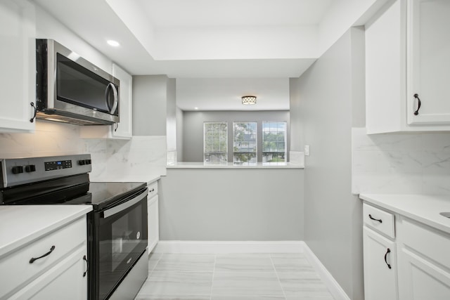 kitchen with white cabinets, stainless steel appliances, light tile patterned floors, and backsplash