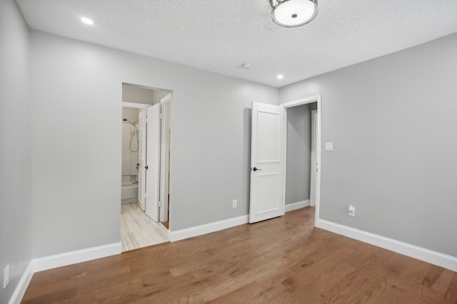 unfurnished bedroom with a textured ceiling, light hardwood / wood-style flooring, and ensuite bathroom