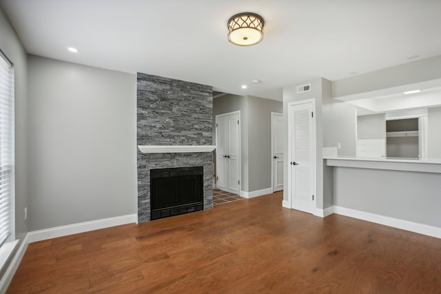 unfurnished living room featuring a stone fireplace and hardwood / wood-style flooring