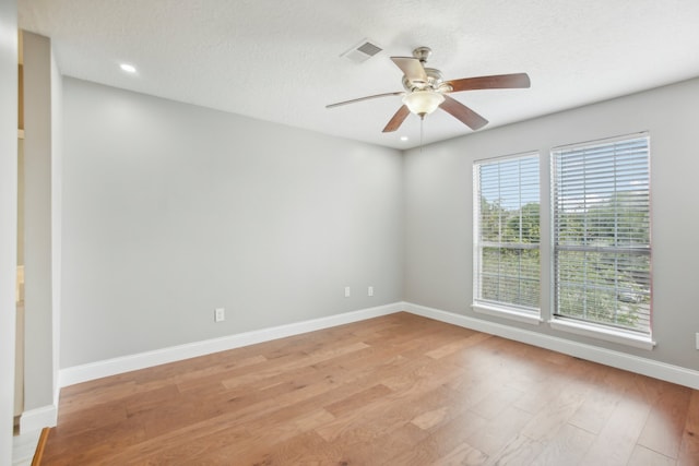 empty room featuring light hardwood / wood-style flooring, a textured ceiling, and ceiling fan