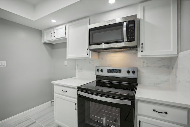 kitchen featuring backsplash, appliances with stainless steel finishes, white cabinets, and light tile patterned floors