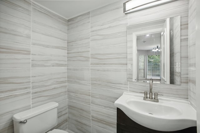 bathroom featuring toilet, vanity, and tile walls