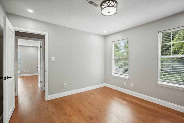 unfurnished room with hardwood / wood-style floors, a textured ceiling, and plenty of natural light