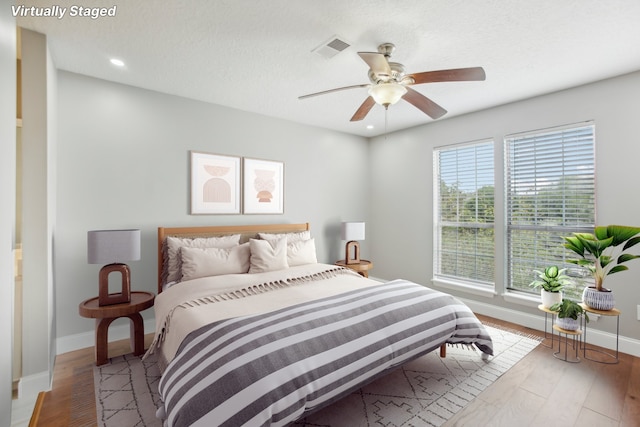 bedroom with ceiling fan, a textured ceiling, and hardwood / wood-style floors