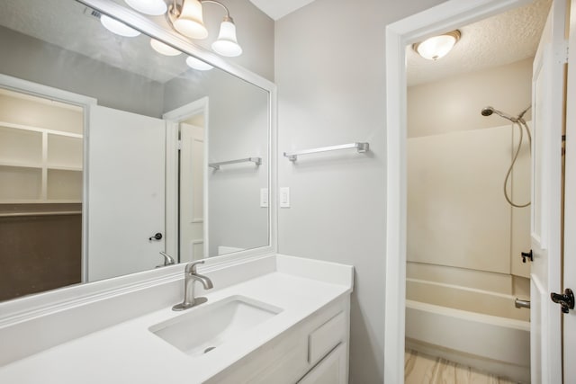 bathroom with vanity, shower / bath combination, and a textured ceiling