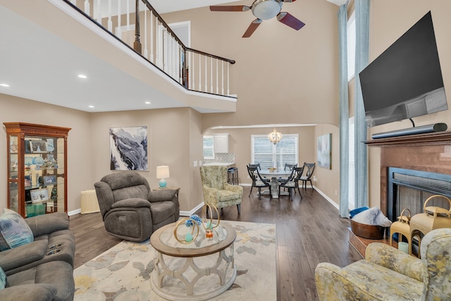 living room featuring a towering ceiling, ceiling fan with notable chandelier, and dark hardwood / wood-style flooring