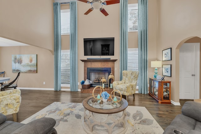 living room with ceiling fan, a towering ceiling, and dark hardwood / wood-style flooring