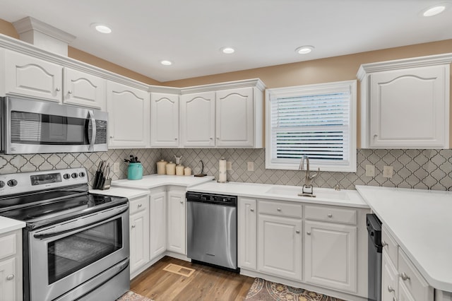 kitchen featuring appliances with stainless steel finishes, light hardwood / wood-style flooring, white cabinetry, and sink