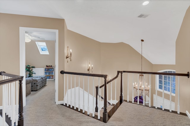 hall with lofted ceiling with skylight, a chandelier, and carpet