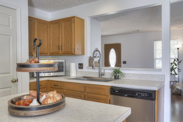 kitchen with a textured ceiling, kitchen peninsula, sink, and appliances with stainless steel finishes