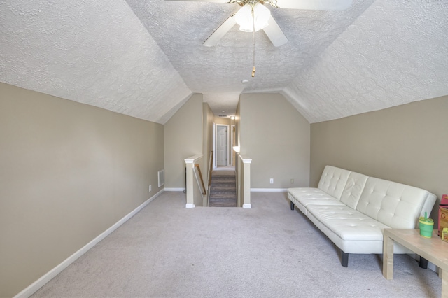 unfurnished room with a textured ceiling, ceiling fan, light carpet, and lofted ceiling