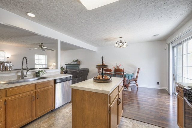 kitchen featuring dishwasher, sink, hanging light fixtures, a textured ceiling, and a kitchen island