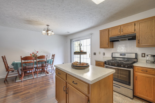 kitchen featuring gas range, a chandelier, a textured ceiling, decorative light fixtures, and a kitchen island