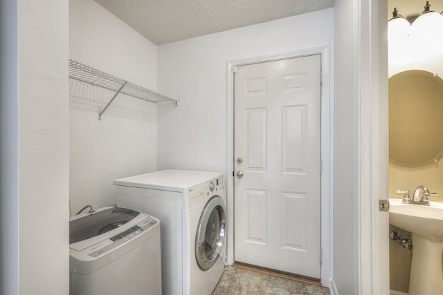 clothes washing area featuring sink, a textured ceiling, and independent washer and dryer