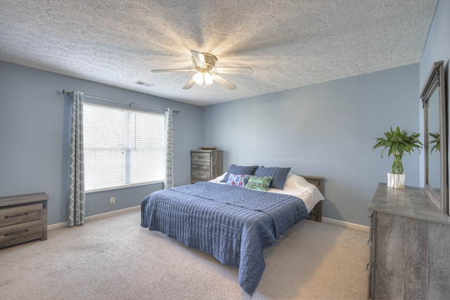 bedroom featuring ceiling fan, light colored carpet, and a textured ceiling