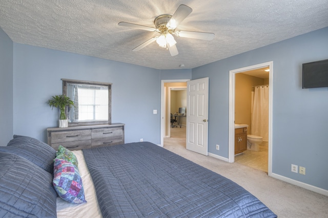 carpeted bedroom featuring ceiling fan, a textured ceiling, and ensuite bath