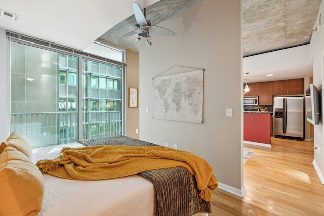 bedroom featuring ceiling fan, access to outside, light hardwood / wood-style flooring, and stainless steel fridge