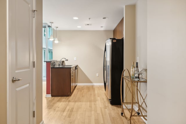 kitchen with sink, light hardwood / wood-style floors, stainless steel refrigerator, and decorative light fixtures