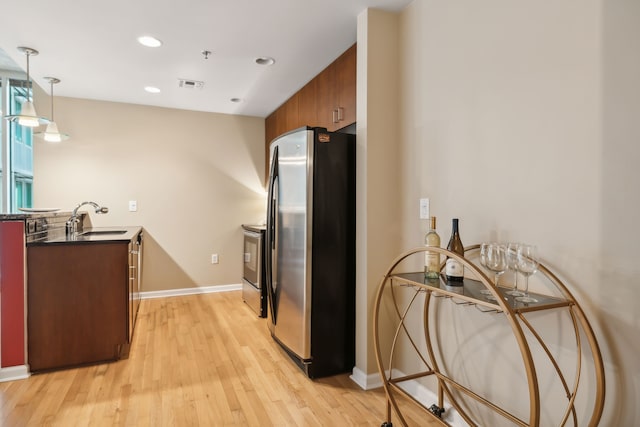 kitchen featuring light hardwood / wood-style floors, appliances with stainless steel finishes, sink, and pendant lighting