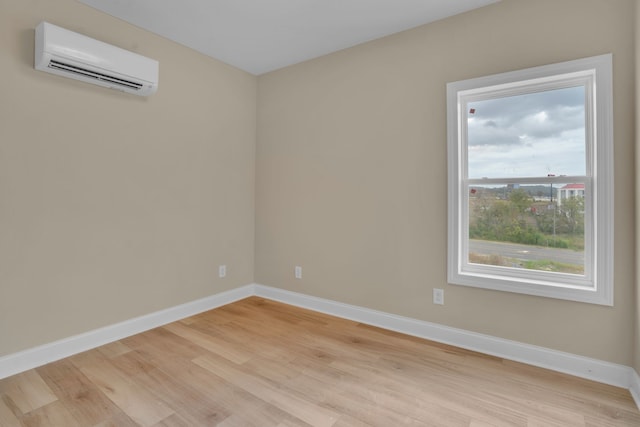 spare room featuring light wood-type flooring and a wall unit AC