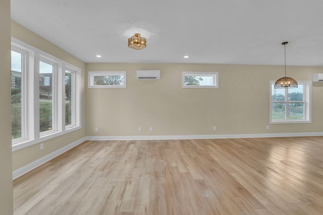 spare room featuring light wood-type flooring and a wall unit AC