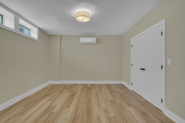 basement with a wall mounted AC and light hardwood / wood-style flooring