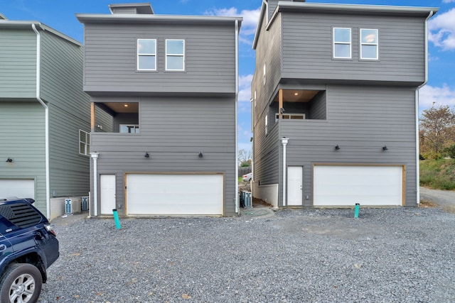 view of front of home featuring a garage, cooling unit, and a balcony