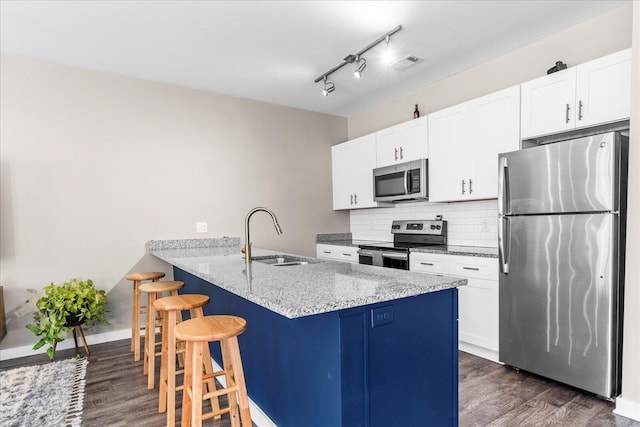 kitchen featuring appliances with stainless steel finishes, sink, kitchen peninsula, white cabinetry, and a breakfast bar