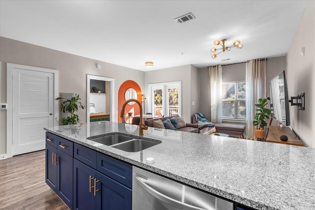 kitchen featuring light stone counters, hardwood / wood-style flooring, stainless steel dishwasher, blue cabinetry, and sink