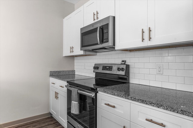 kitchen with decorative backsplash, dark wood-type flooring, stainless steel appliances, dark stone counters, and white cabinetry