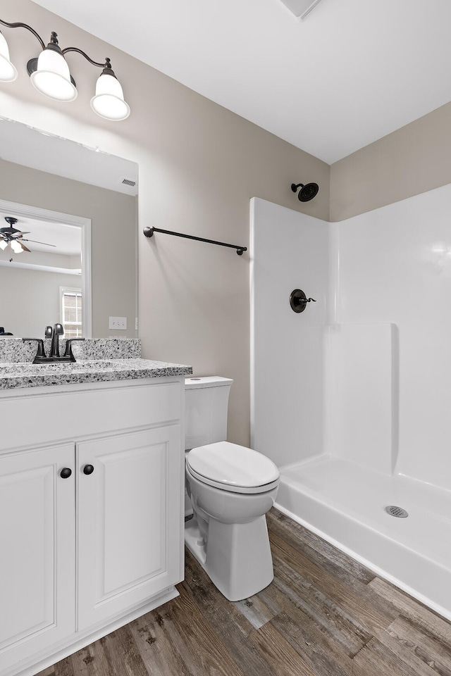 bathroom with toilet, ceiling fan, walk in shower, vanity, and hardwood / wood-style flooring