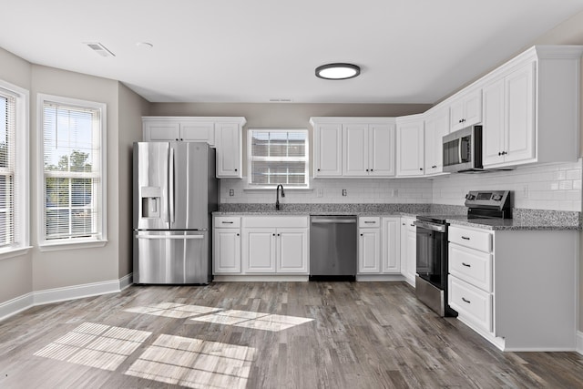 kitchen with white cabinetry, stainless steel appliances, light hardwood / wood-style floors, and plenty of natural light