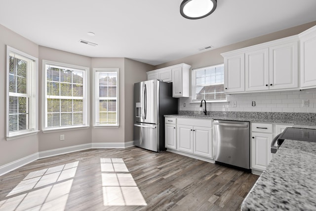 kitchen with white cabinets, stainless steel appliances, and light stone counters