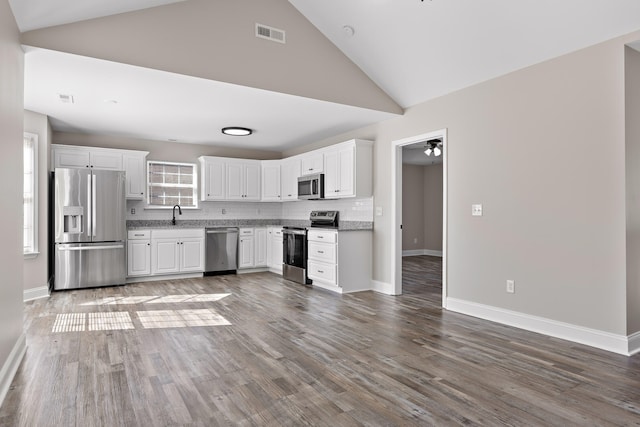 kitchen with white cabinets, dark hardwood / wood-style flooring, appliances with stainless steel finishes, high vaulted ceiling, and ceiling fan