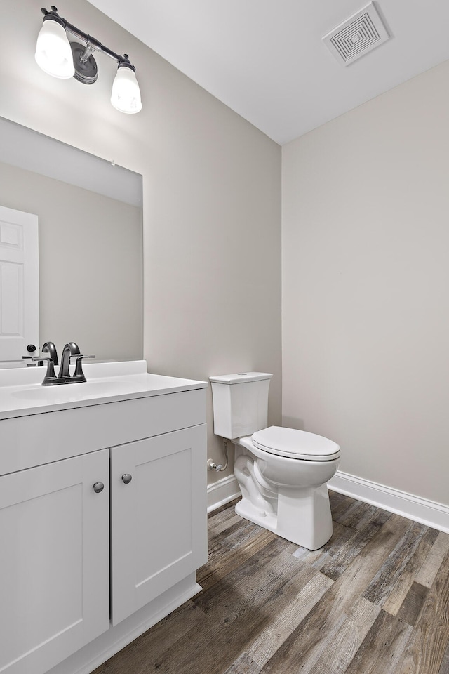 bathroom with toilet, hardwood / wood-style floors, and vanity