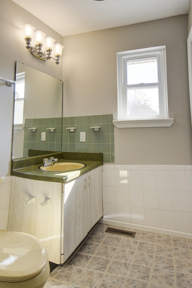 bathroom featuring tile patterned floors, tile walls, vanity, and a textured ceiling