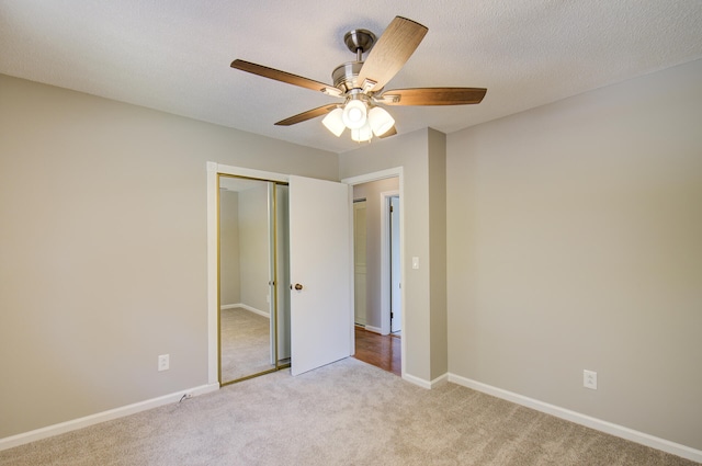 unfurnished bedroom with light carpet, a textured ceiling, a closet, and ceiling fan