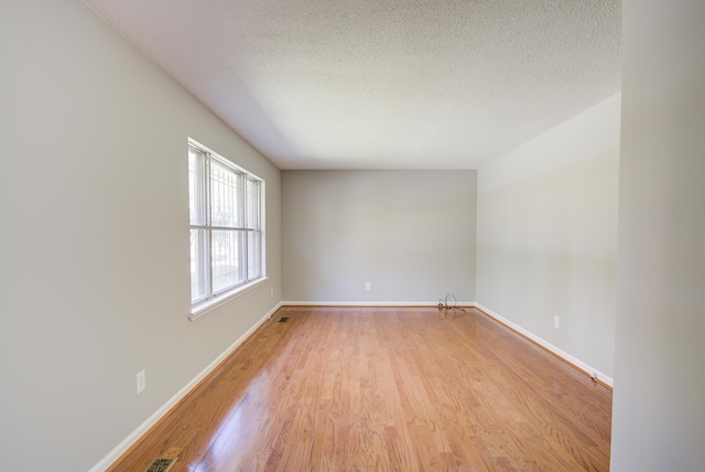 empty room with a textured ceiling and light wood-type flooring