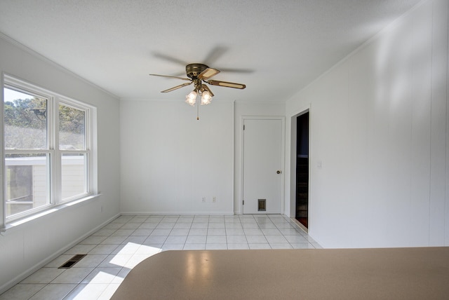 unfurnished room with light tile patterned floors, a textured ceiling, ceiling fan, and ornamental molding